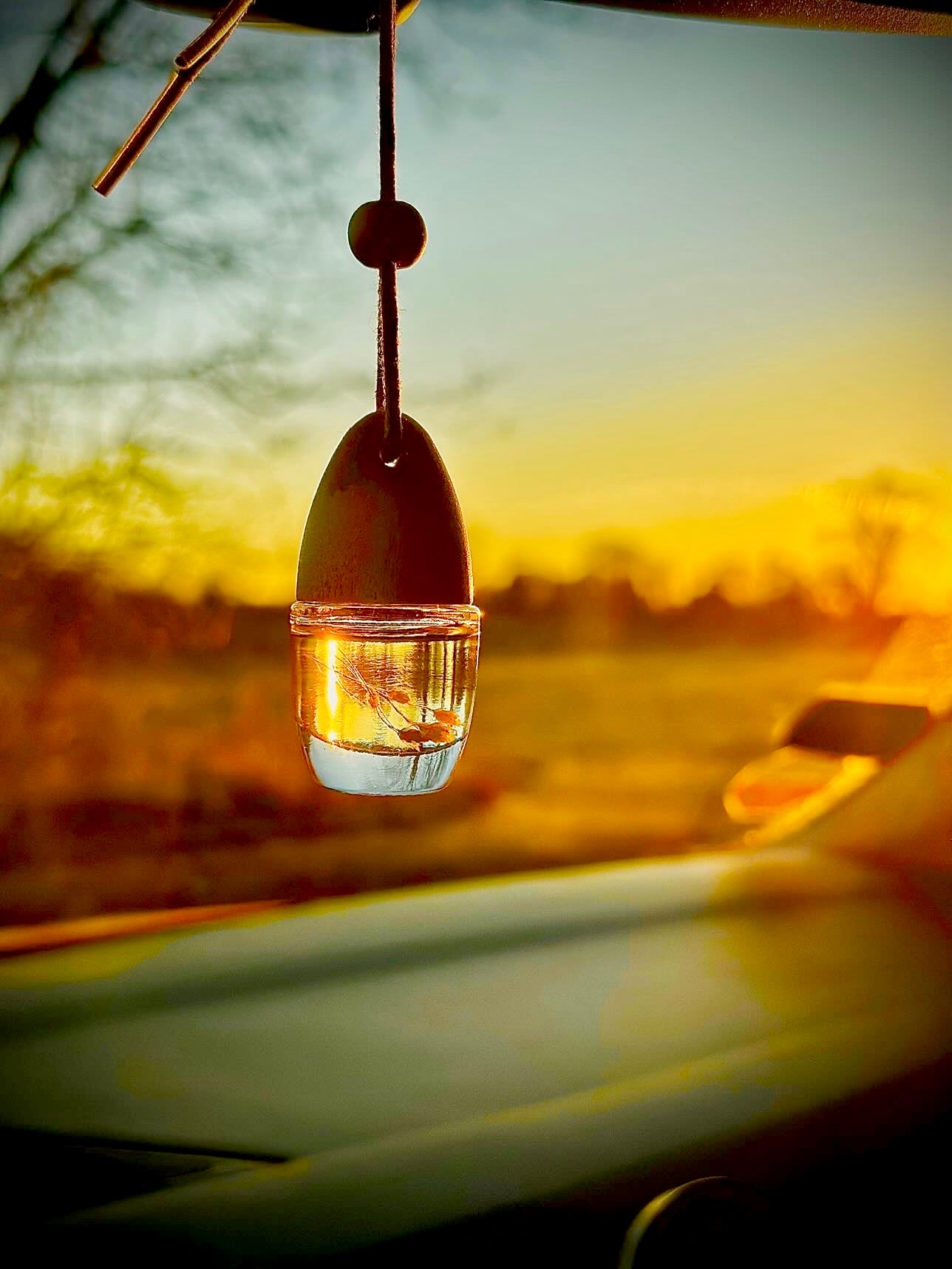 „Natürlicher Autoduft mit Holzdeckel – Duft Apfelkuchen Zimt von NEA Home & Decor, handgemacht und vegan, fotografiert im warmen Sonnenlicht im Auto“